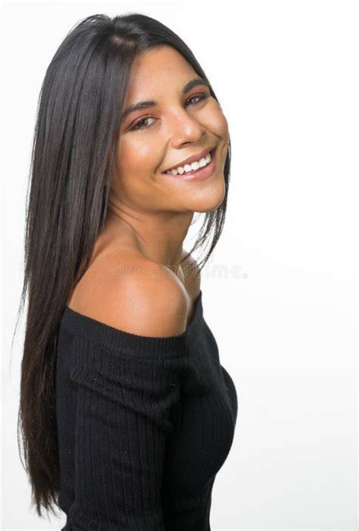 a woman with long dark hair wearing a black dress and holding her hand